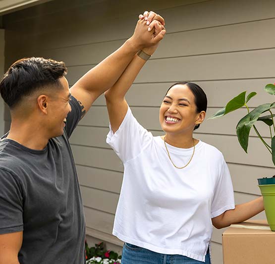 Couple high fiving in front of new home