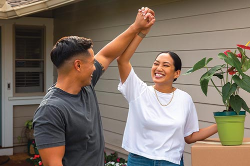 Couple giving a high five in front of home